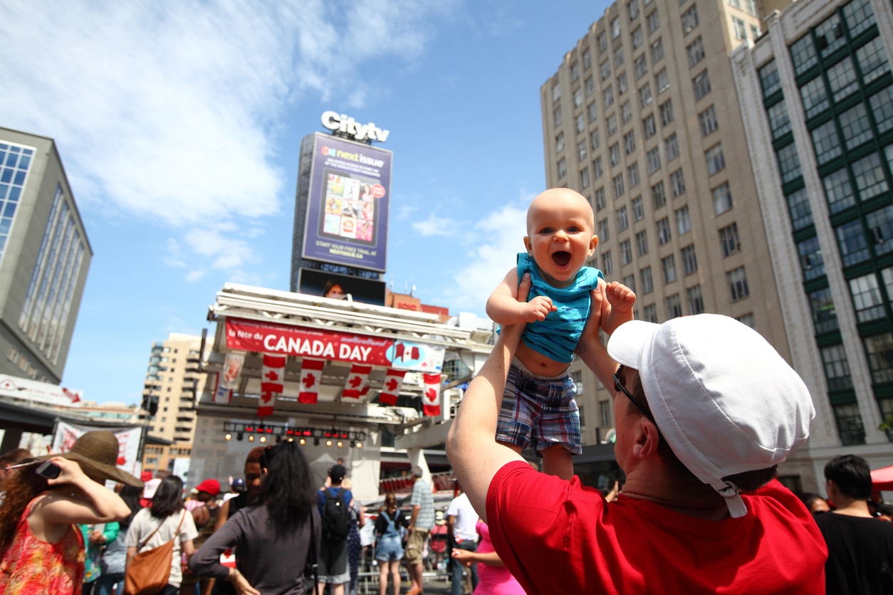 Canada Day celebration at Yonge-Dundas Square in Toronto, with Canadian flags and crowd gathered under city lights