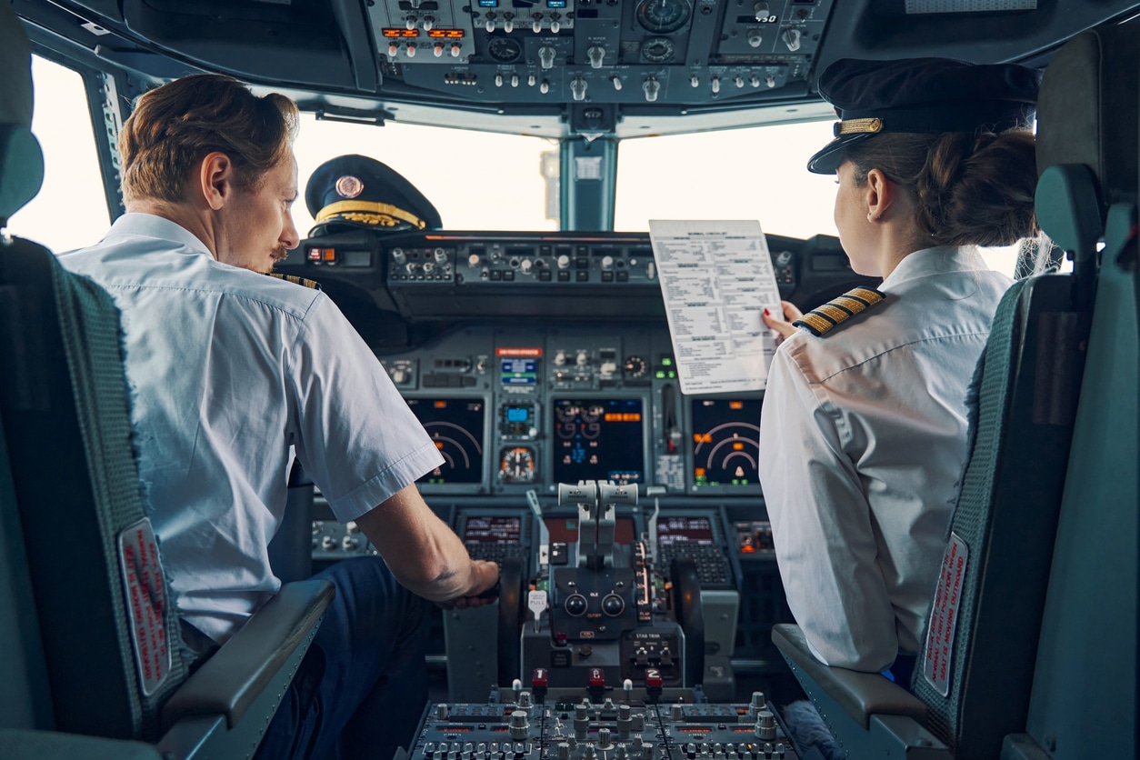 Two airline pilots reviewing flight documents inside cockpit — example of frequent travelers impacted by US tax rules