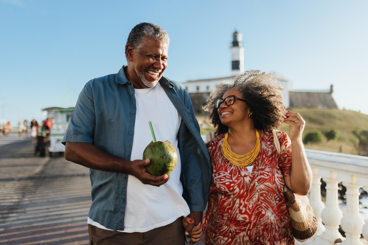 Happy retired couple walking outdoors by the ocean, symbolizing financial planning and 401k considerations when renouncing US citizenship.
