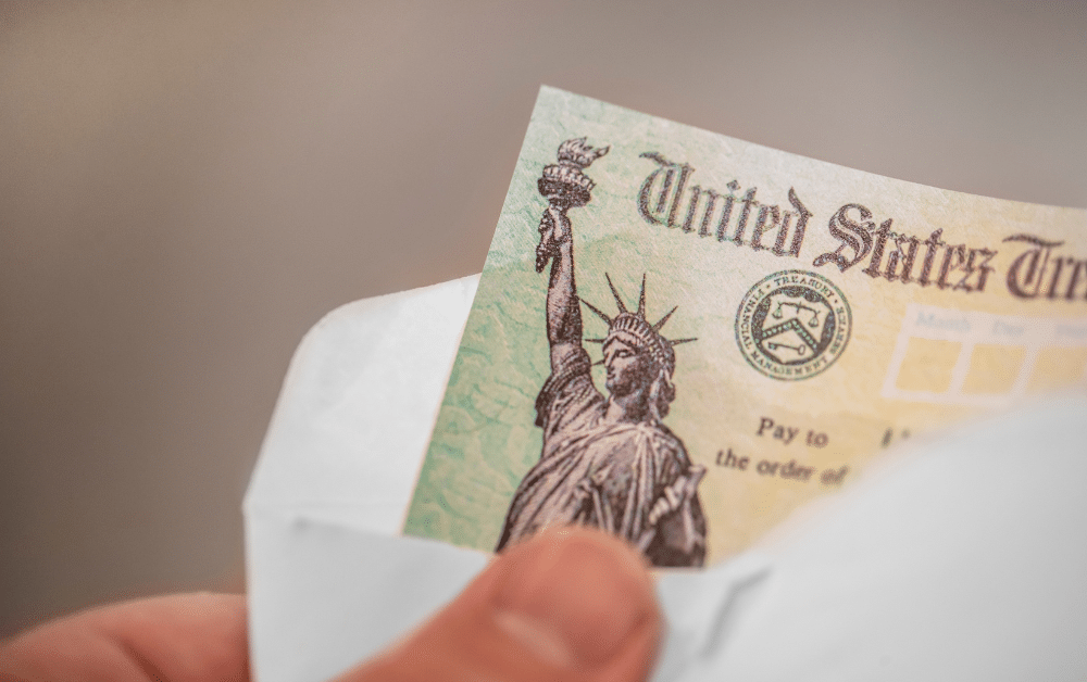 Hand holding U.S. Treasury check with Statue of Liberty design, representing federal paper checks that will be eliminated for expat tax refunds and benefits after September 30, 2025